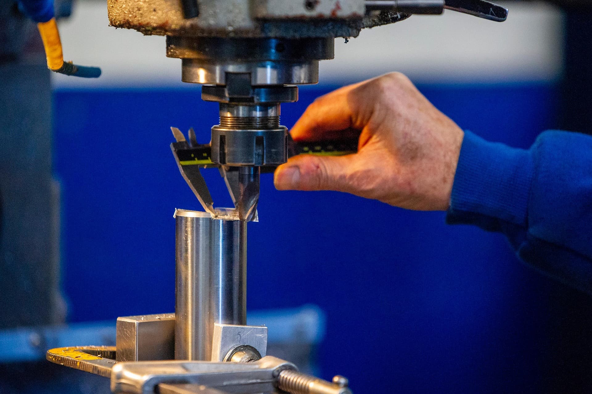 Worker measuring a metal component at a machine