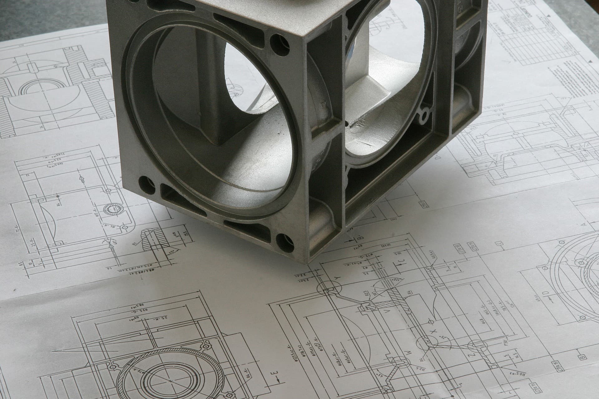 Machined metal component resting on technical drawings